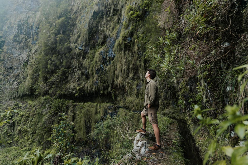 A man explores a moss-covered cliff in Portugal, showcasing adventure and natural beauty.