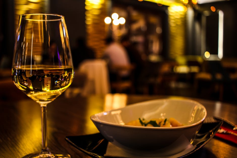 A classy dining setup featuring a glass of white wine in a cozy restaurant setting