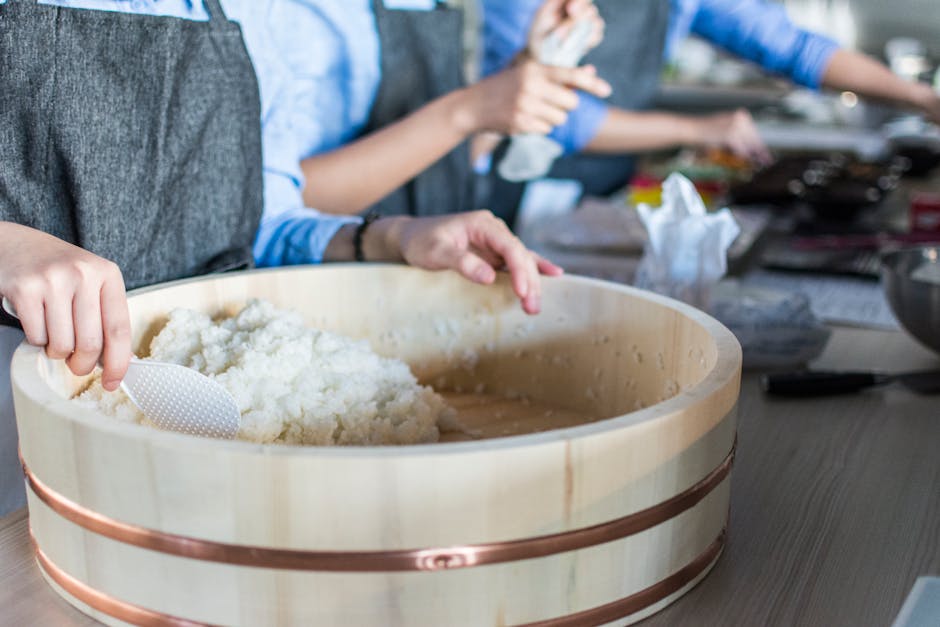 Close-up of sushi rice being prepared by chefs in a bright modern kitchen setting