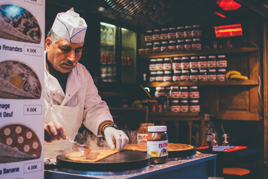 A chef skillfully prepares a Nutella crepe in a cozy Parisian café. Indoor ambiance and culinary expertise