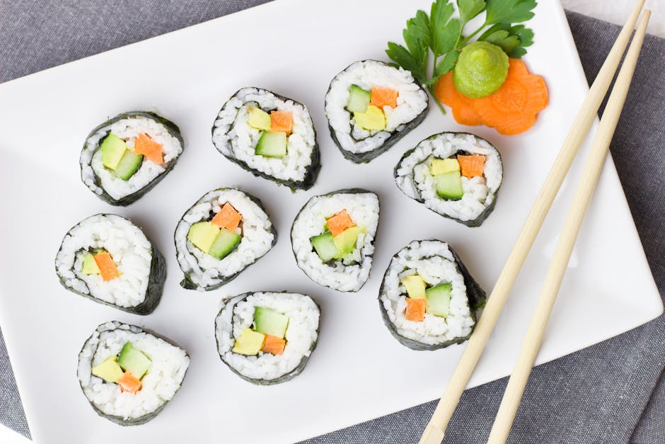 Top view of vegetable sushi rolls with chopsticks and wasabi on a white plate