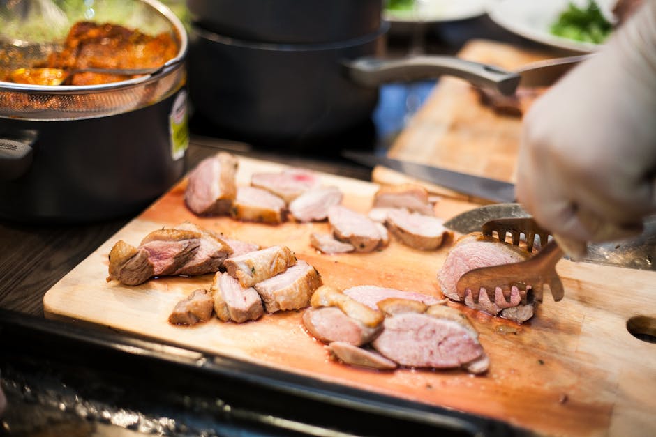 Close-up of cooked meat being sliced on a wooden board, highlighting food preparation