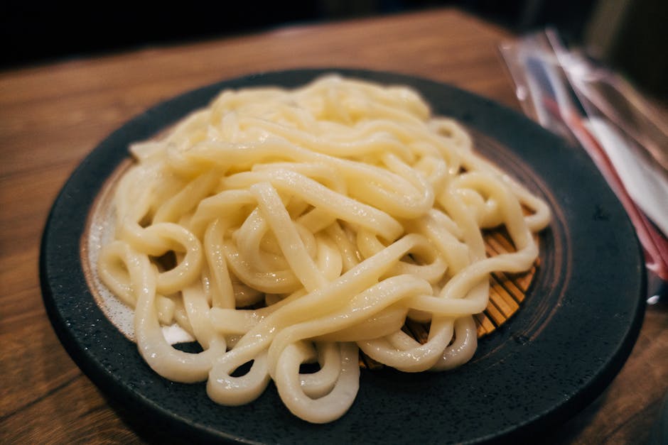 Tantalizing close-up of cooked udon noodles served on an elegant dark plate